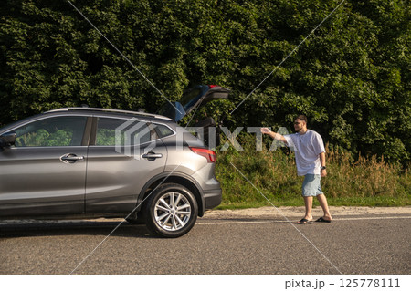 Man with Backpack at Open Car Trunk Man with Backpack at Open Car Trunk 125778111
