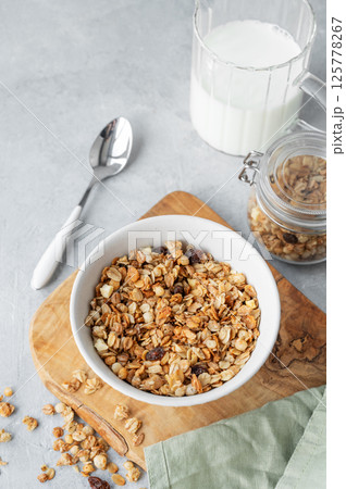 Homemade baked granola or muesli in a bowl on a wooden board on a light background 125778267