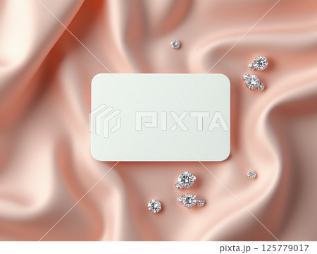 Elegant presentation of a blank card surrounded by sparkling gems on soft satin fabric 125779017