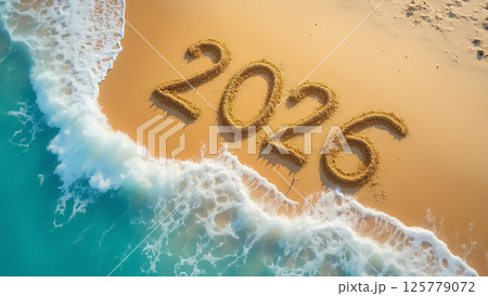 Beach sand art displays the number 2026 as waves gently wash over the shore at sunset 125779072