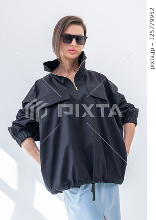 Elegant woman in black windbreaker jacket and light blue skirt on white background. Fashionable female style. Studio photography. Vertical photo. High quality photo Elegant woman in black windbreaker jacket and light blue skirt on white background. Fashionable female style. Studio photography. Vertical photo. High quality photo 125779952