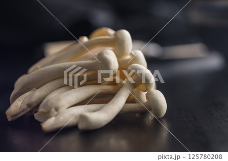 Raw white shimeji mushrooms on black table. Raw white shimeji mushrooms on black table. 125780208