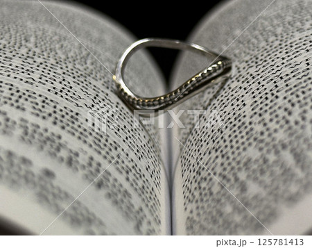 Silver Ring Creating a Heart Shadow in an Open Book Silver Ring Creating a Heart Shadow in an Open Book 125781413