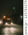 An old school bus drives down a foggy street at night 125781579