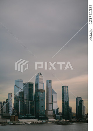 City skyline with cloudy sky and water in the foreground City skyline with cloudy sky and water in the foreground 125781582