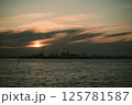 A stunning sunset lights up the water with a city skyline behind 125781587