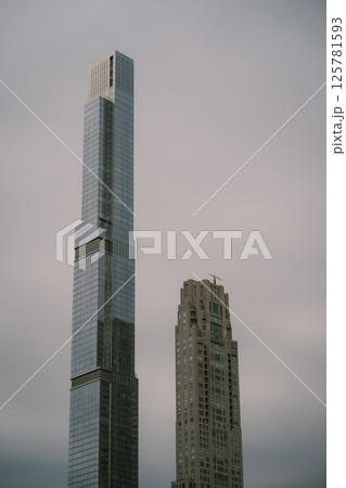 Two tall buildings stand next to each other on a cloudy day 125781593