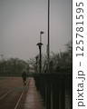 A person is leisurely walking down a sidewalk on a track during the rain 125781595