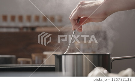 man hand stir fettuccine in boiling water in saucepan man hand stir fettuccine in boiling water in saucepan 125782138