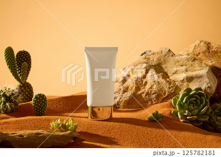 Unlabeled tube displayed on dry desert sand, surrounded by rough rocks, a few rotten logs are scattered about. Succulents grow from the cracks in the rocks, their roots digging deep into the ground. 125782181