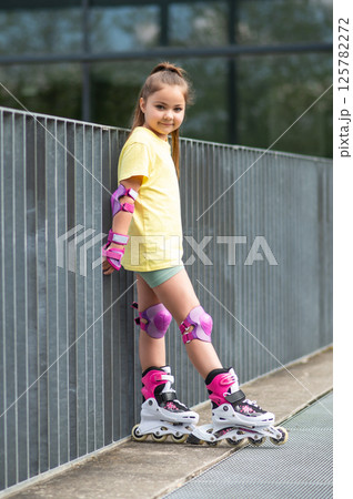 Little female skater practicing rollerblading skills for leisure 125782272