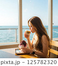 「海辺のカフェでかき氷とコーヒーを楽しむ女性」夏のリゾート気分を味わうひととき 125782320