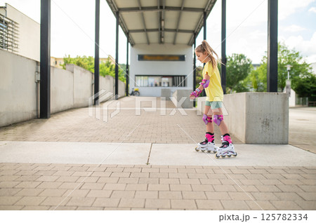 Little female skater riding roller-blades outdoors having fun 125782334