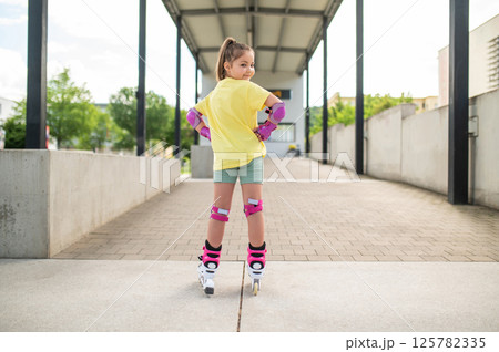 Little girl roller-skating outside in stadium Little girl roller-skating outside in stadium 125782335