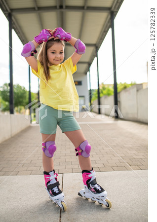 Little girl roller-skating outside in stadium Little girl roller-skating outside in stadium 125782339