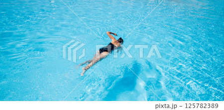 Woman in black swimsuit swimming in the pool. Woman in black swimsuit swimming in the pool. 125782389