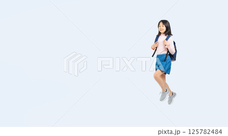 リュックを背負ってジャンプする小学生の女の子の全身写真 リュックを背負ってジャンプする小学生の女の子の全身写真 125782484