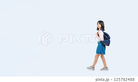 リュックを背負って横向きに歩く小学生の女の子の全身写真 125782488