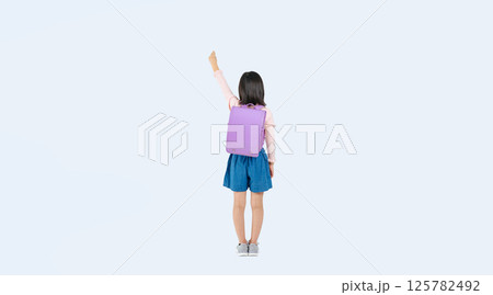 ガッツポーズするランドセルを背負った小学生の女の子の後ろ姿の全身写真 125782492