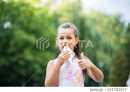 A pretty girl enjoying a delicious ice cream in the summer. Girl with ice cream on a walk in the park. A pretty girl enjoying a delicious ice cream in the summer. Girl with ice cream on a walk in the park. 125782917