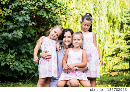 The girls wrap their arms around their mother, enjoying the moment. The twins, identical in looks and laughter, hug her tightly. 125782928