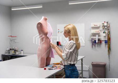 Contented caucasian fashion designer working in her studio Contented caucasian fashion designer working in her studio 125783123