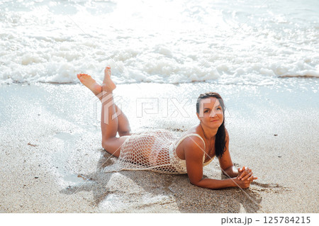woman in a light swimsuit swims on a sandy sea beach woman in a light swimsuit swims on a sandy sea beach 125784215
