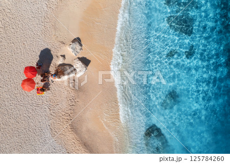 Aerial view of red umbrellas, sandy beach and blue sea with waves 125784260