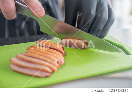 The chef slices the roast duck. The chef slices the roast duck. 125784322