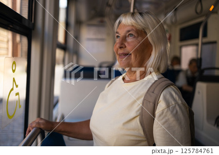 Senior woman traveling by public transport, enjoying the ride in a tram 125784761