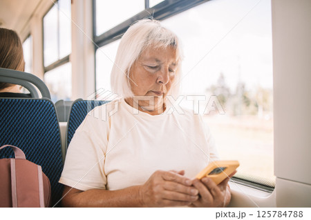 Senior woman using smartphone on a bus while traveling. Senior woman using smartphone on a bus while traveling. 125784788