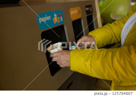 Person throwing ice cream spoon into recycling bin, sorting waste, environmental protection 125784807