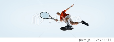 Bottom view of man, tennis player leaps for overhead shot during dynamic match moment against white studio background. 125784811