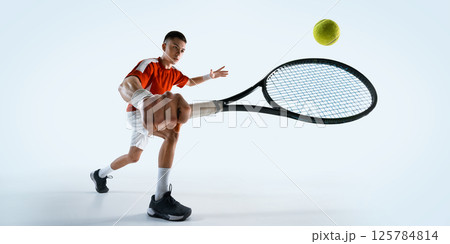 Low angle view of man, tennis player prepares for return shot with intense focus and readiness against white studio background. 125784814
