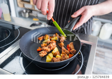 The chef fries pork in sweet and sour.  125784839