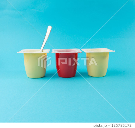 Yogurt cups set, pink and yellow fruit yoghurt in plastic pots, milk pudding container with spoon Yogurt cups set, pink and yellow fruit yoghurt in plastic pots, milk pudding container with spoon 125785172