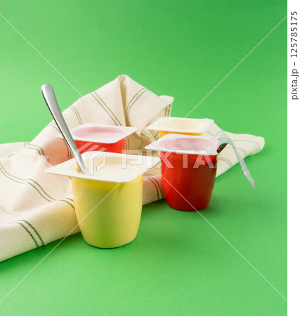 Yogurt cups set, pink and yellow fruit yoghurt in plastic pots, milk pudding container with spoon Yogurt cups set, pink and yellow fruit yoghurt in plastic pots, milk pudding container with spoon 125785175