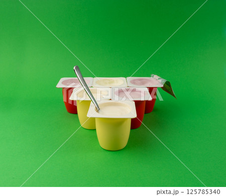 Yogurt cups set, pink and yellow fruit yoghurt in plastic pots, milk pudding container with spoon 125785340
