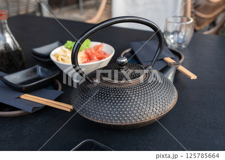Japanese tea pot, black metal teapot, traditional iron kettle for tea drinking while waiting for sushi Japanese tea pot, black metal teapot, traditional iron kettle for tea drinking while waiting for sushi 125785664