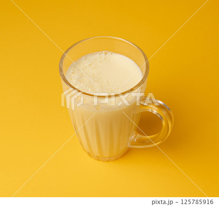 Vanilla milk shake in glass. Milkshake on yellow background, white whey protein smoothie Vanilla milk shake in glass. Milkshake on yellow background, white whey protein smoothie 125785916