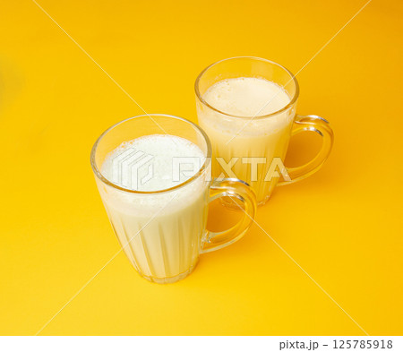 Vanilla milk shake in glass. Milkshake on yellow background, white whey protein smoothie Vanilla milk shake in glass. Milkshake on yellow background, white whey protein smoothie 125785918