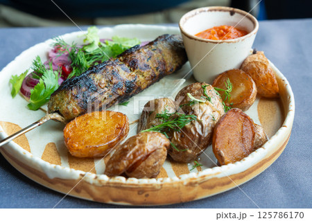 Georgian lula kebab plate. Bbq skewer, traditional barbecue dish with baked potatoes, sauce 125786170
