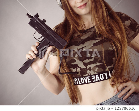 Woman wearing headphones holding gun 125786616