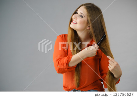Woman combing her brown hair 125786627