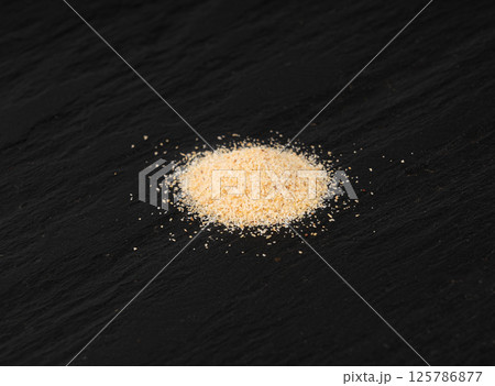 Garlic powder pile, dried granulated chopped crushed garlic cloves, cut into small pieces Garlic powder pile, dried granulated chopped crushed garlic cloves, cut into small pieces 125786877