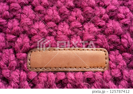 Knitted woolen fabric pattern in rich magenta. Macro texture of a cozy sweater, thick woven yarn 125787412
