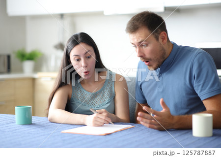 Surprised interracial couple checking contract at home Surprised interracial couple checking contract at home 125787887