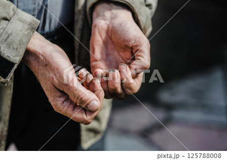 The photo shows old, dirty hands stretched out in a plea for alms, revealing a life of hardship. Dirty old man's worn-out hands ask for alms. The photo shows old, dirty hands stretched out in a plea for alms, revealing a life of hardship. Dirty old man's worn-out hands ask for alms. 125788008