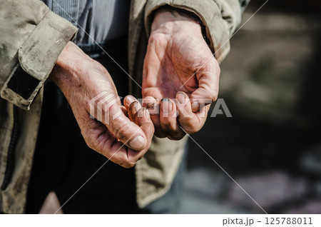 Wrinkled and covered in dirt, the hands tremble as they reach out, symbolizing desperation and struggle. The hands of a beggar ask for alms. Wrinkled and covered in dirt, the hands tremble as they reach out, symbolizing desperation and struggle. The hands of a beggar ask for alms. 125788011