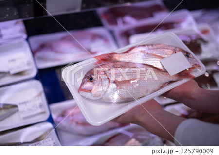 パックに入った鯛を持った子供の手 125790009